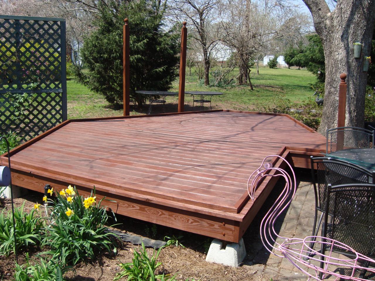 Finished custom-shaped garden deck with redwood staining, built around an existing tree